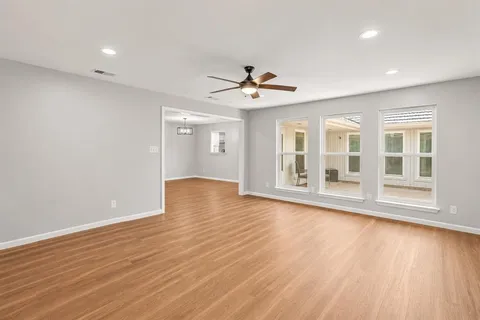 a view of an empty room with a window and wooden floor