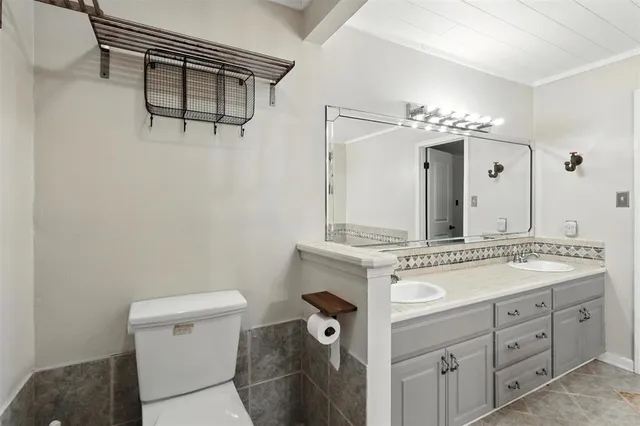 a bathroom with a granite countertop sink a toilet and a mirror