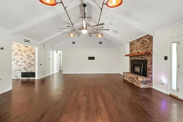 an empty room with wooden floor fan and window