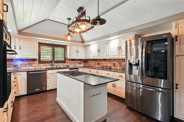 a kitchen with stainless steel appliances granite countertop a sink a stove and refrigerator