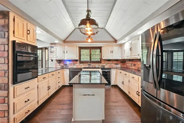 a kitchen with stainless steel appliances kitchen island granite countertop a stove a sink and a refrigerator