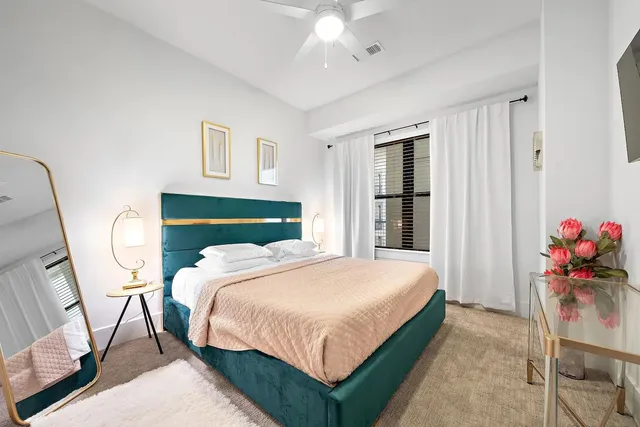 a bedroom with a bed painting on wall and a potted plant