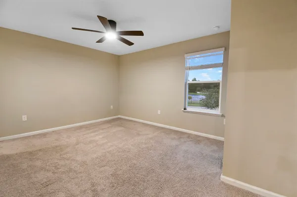 an empty room with a ceiling fan and window