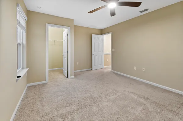 a view of an empty room and chandelier fan