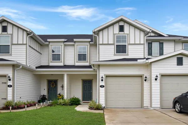 a view of a white house with large windows and a yard