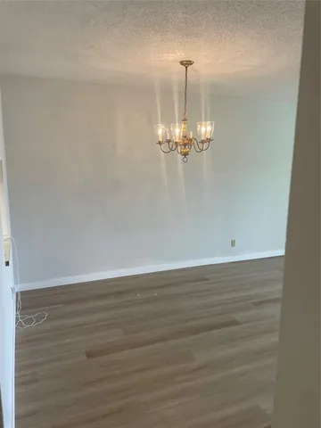 a view of a room with wooden floor and chandelier