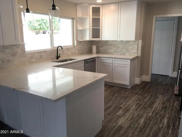 a kitchen with stainless steel appliances granite countertop a sink a window and wooden floor