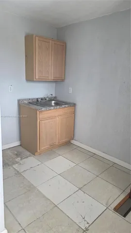 a room with granite countertop a sink and a stove top oven