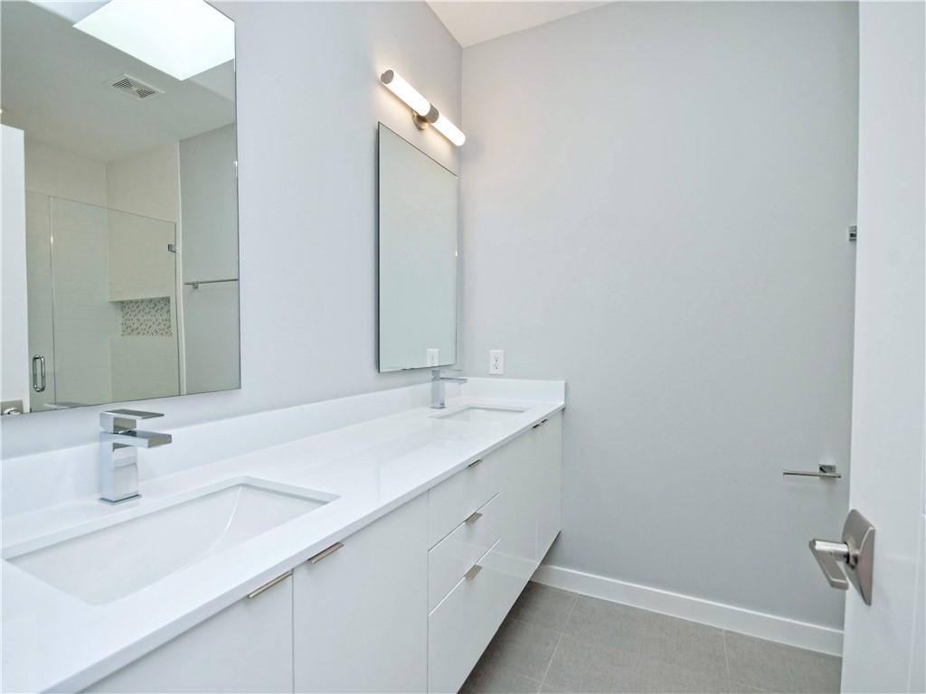 2108 Tillery Street, Unit 2102 Austin, TX 78723 - Photo 13 of 26 The spa-like en-suite features a double vanity with a quartz countertop and undermount sinks.
