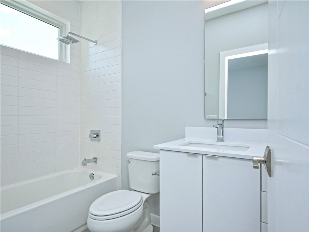 2108 Tillery Street, Unit 2102 Austin, TX 78723 - Photo 20 of 26 The en-suite is equipped with a single vanity and a soaking tub/shower combo with subway tile surround.