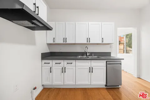a kitchen with stainless steel appliances granite countertop a sink a stove and white cabinets