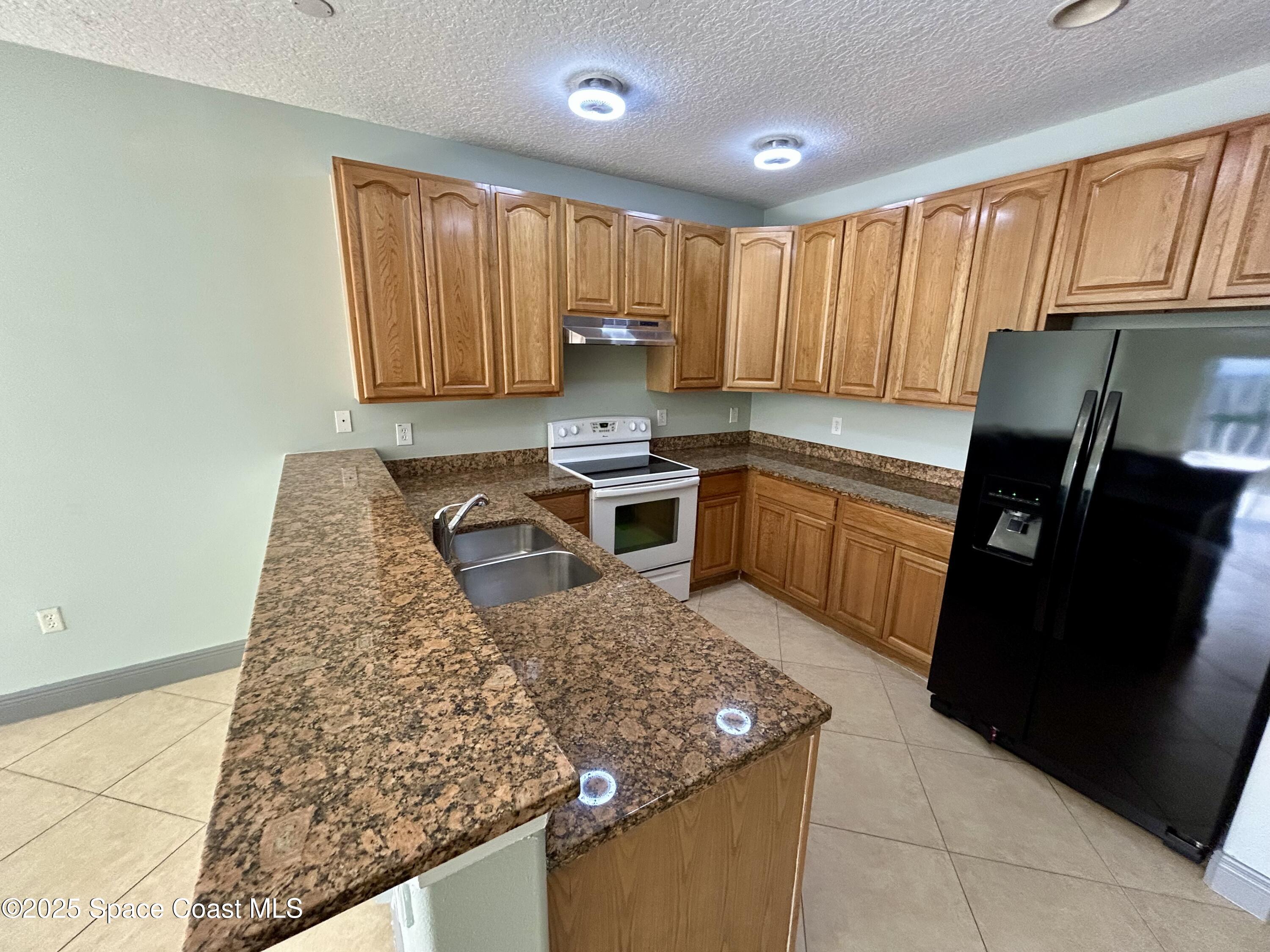 910 Twisting Branch Court Melbourne, FL 32935 - Photo 12 of 24 a kitchen with a sink stove and refrigerator
