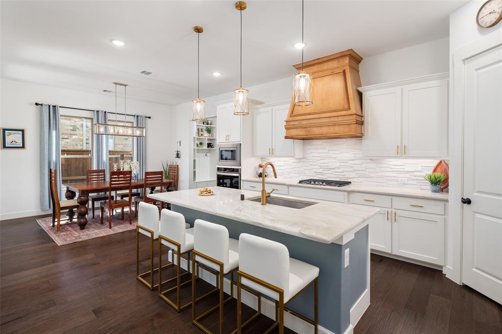 4881 Miles Way Fairview, TX 75069 - Photo 8 of 39 a kitchen with stainless steel appliances granite countertop a stove a sink a oven a dining table and chairs with wooden floor