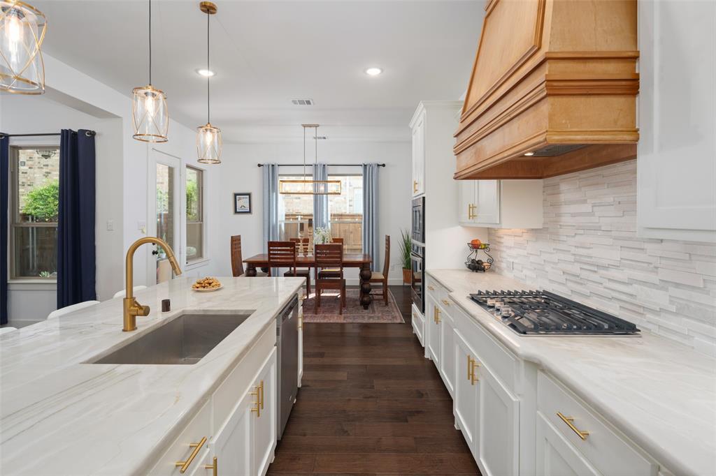 4881 Miles Way Fairview, TX 75069 - Photo 9 of 39 a kitchen with stainless steel appliances a stove a sink a kitchen island with wooden cabinets and floor