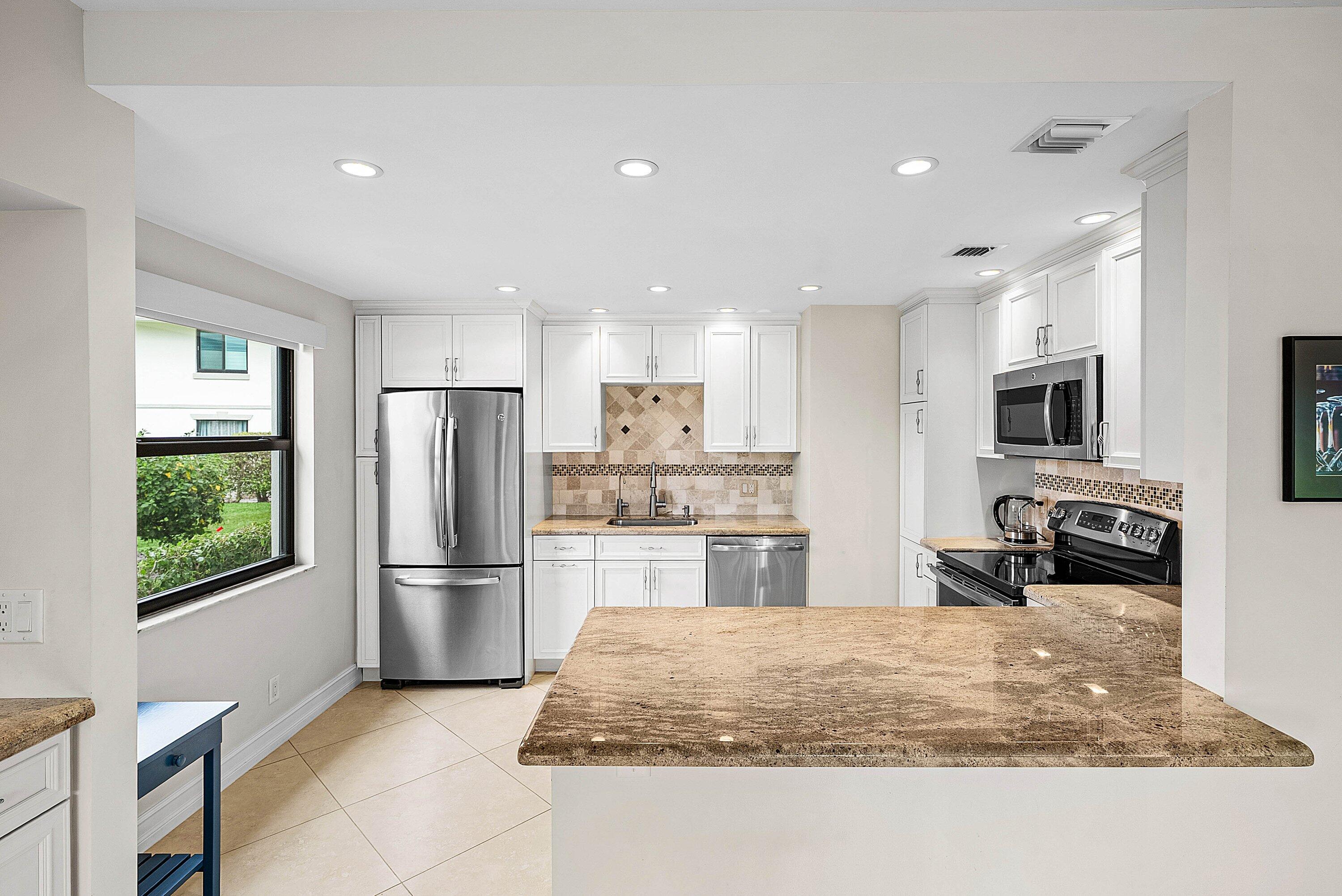 10171 Quail Covey Road, Unit HIBISCUS N Boynton Beach, FL 33436 - Photo 6 of 50 a kitchen with stainless steel appliances granite countertop a refrigerator and a stove top oven