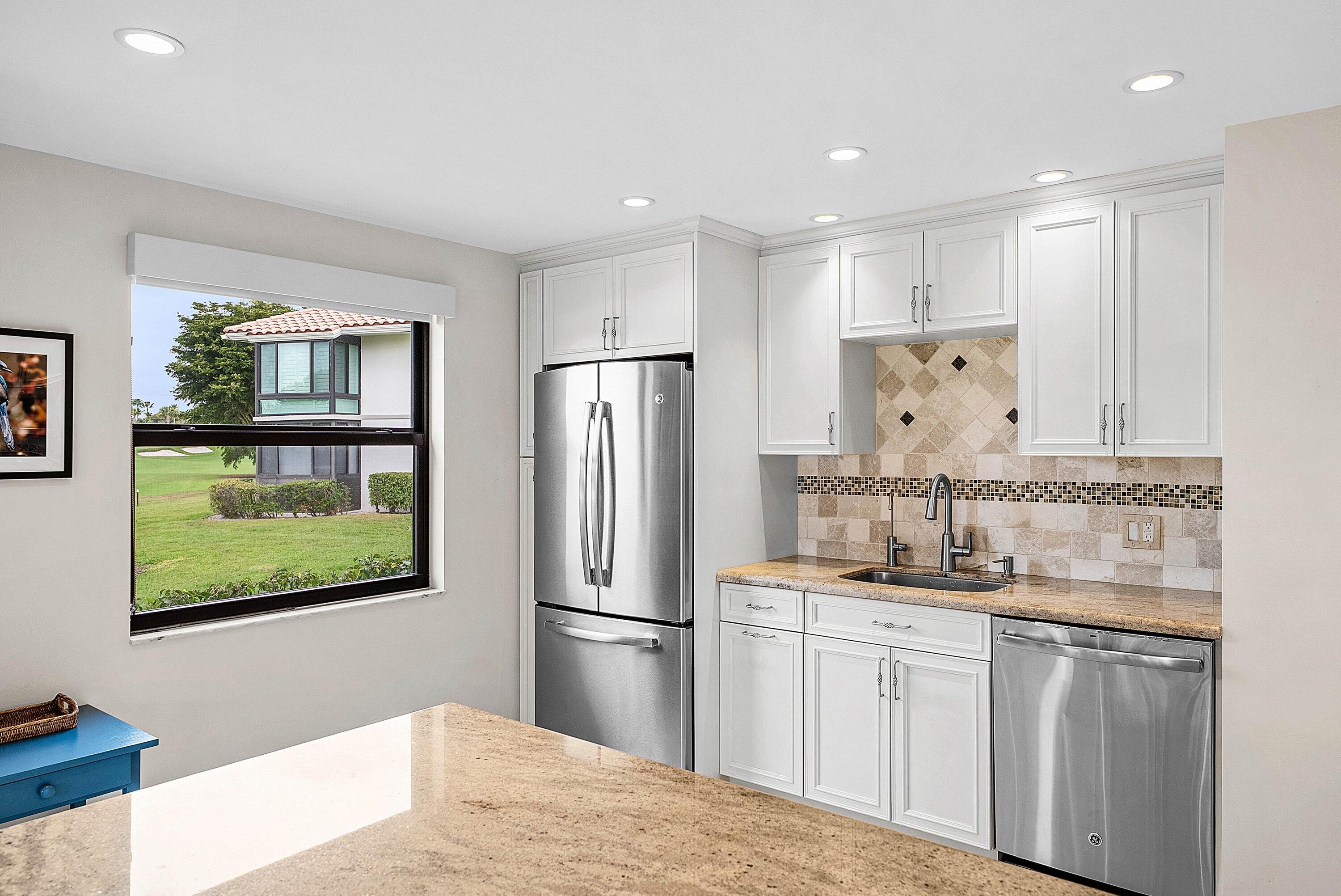 10171 Quail Covey Road, Unit HIBISCUS N Boynton Beach, FL 33436 - Photo 10 of 50 a kitchen with stainless steel appliances granite countertop a refrigerator and a sink