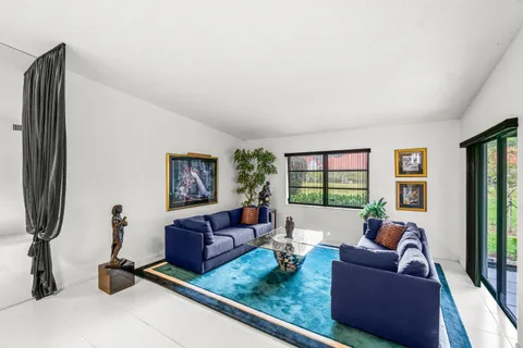 a living room with furniture two window and a flat screen tv