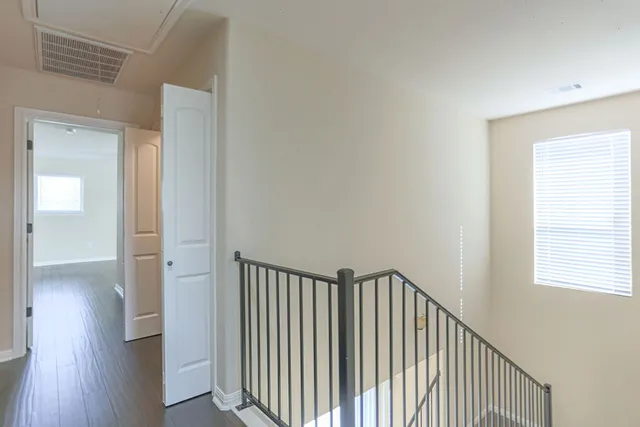 a view of a hallway with wooden floor and a window
