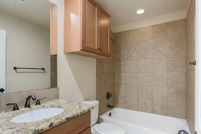 a bathroom with a granite countertop sink a mirror and a bathtub