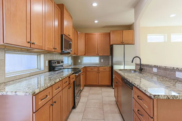 a kitchen with kitchen island granite countertop a sink stainless steel appliances and cabinets