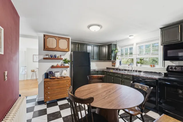 a kitchen with stainless steel appliances granite countertop a stove a refrigerator a sink a dining table and chairs with wooden floor