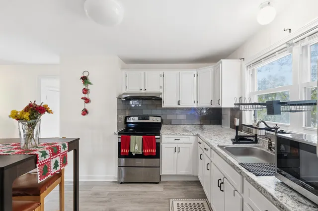 a kitchen with granite countertop a sink dishwasher a stove and a refrigerator