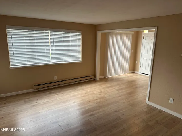 a view of an empty room with wooden floor and a window