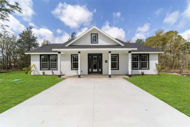 a front view of a house with a garden and trees
