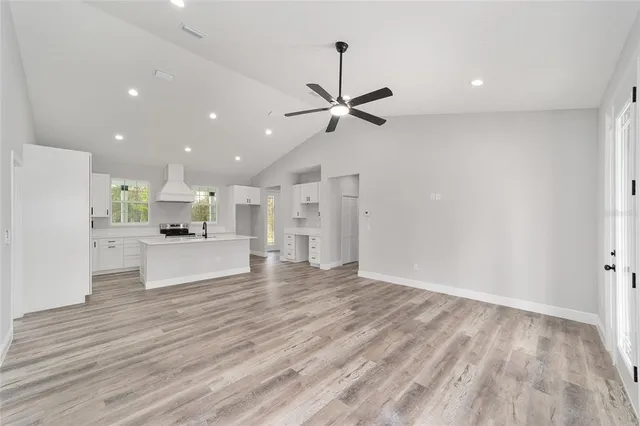 a kitchen with a sink dishwasher stove and white cabinets with wooden floor