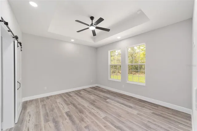an empty room with wooden floor fan and windows