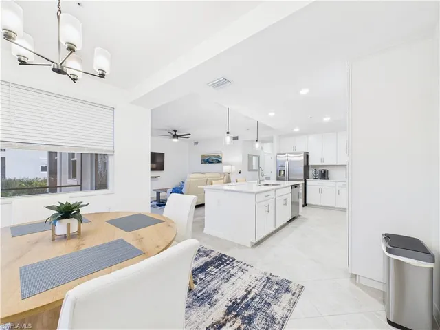 a large white kitchen with a stove a sink dishwasher and a dining table with kitchen view