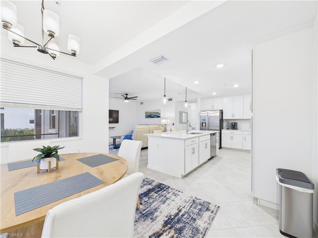 5527 Double Eagle Circle, Unit 3817 Ave Maria, FL 34142 - Photo 5 of 26 a large white kitchen with a stove a sink dishwasher and a dining table with kitchen view