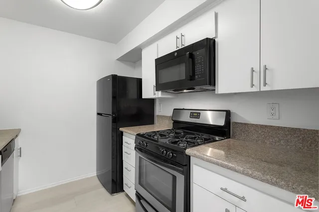 a kitchen with stainless steel appliances granite countertop white cabinets and a stove top oven