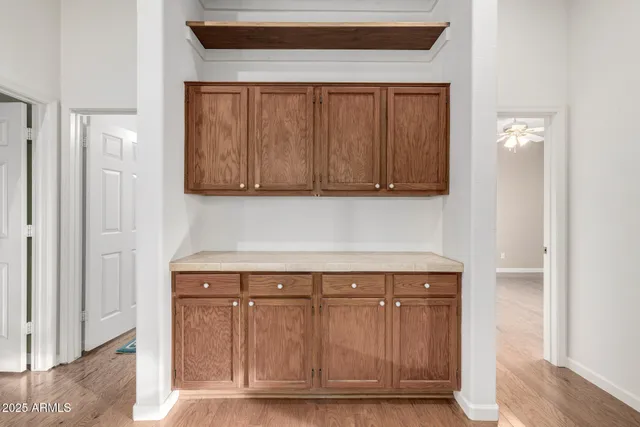 a view of an empty room with wooden floor and a ceiling fan