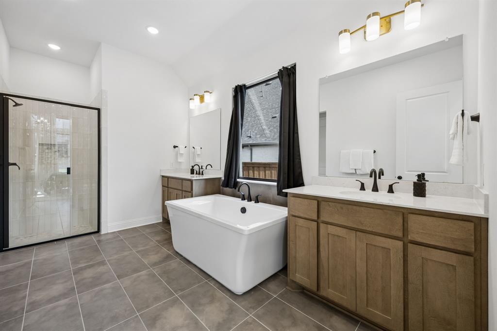 1717 Tolleson Drive Fort Worth, TX 76008 - Photo 15 of 40 a bathroom with a double vanity sink a mirror and a bathtub
