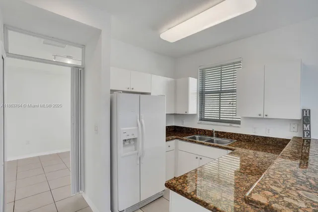 a kitchen with white cabinets and sink