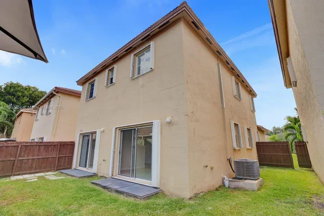 a view of backyard with barbeque grill potted plants and wooden fence
