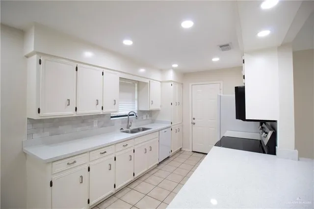 a large white kitchen with white cabinets and a sink