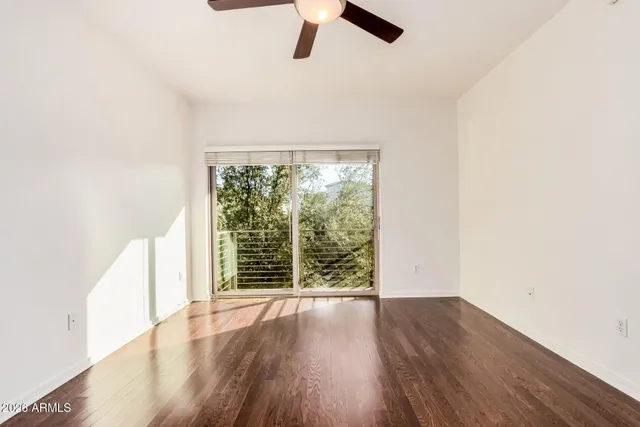 an empty room with wooden floor fan and windows