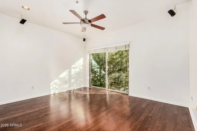 an empty room with wooden floor fan and windows