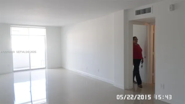 a view of a refrigerator in kitchen and an empty room