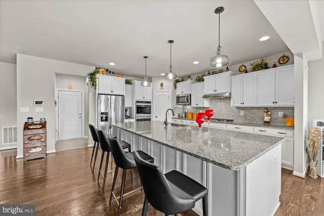 a kitchen with stainless steel appliances kitchen island granite countertop a dining table chairs and white cabinets