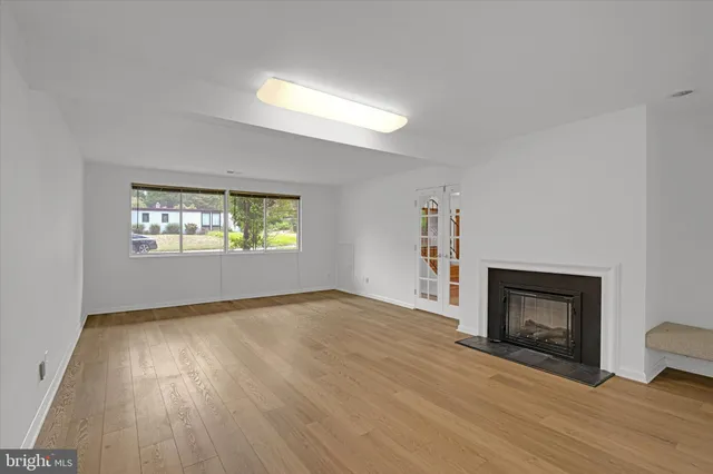 an empty room with windows and fireplace