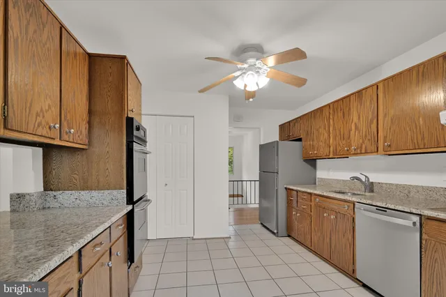 a kitchen with stainless steel appliances granite countertop a refrigerator a sink dishwasher and white cabinets with wooden floor