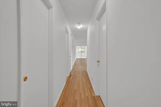 a view of a hallway with wooden floor and closet