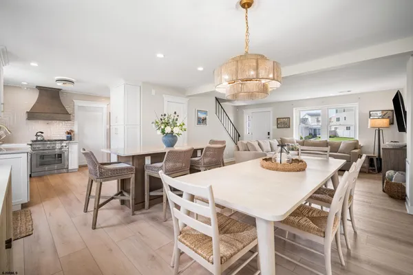 a view of a dining room and livingroom with furniture wooden floor a chandelier