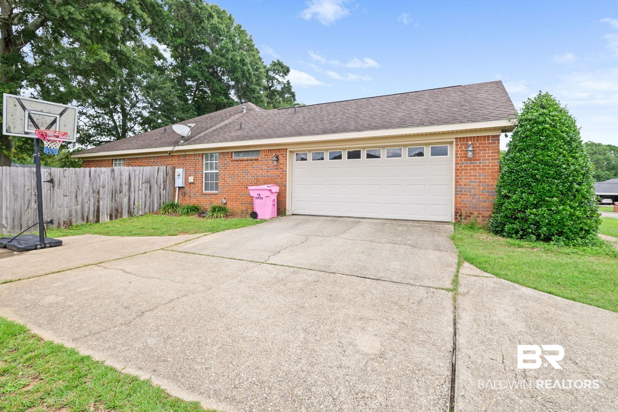 9422 Labrador Run South Mobile, AL 36695 - Photo 35 of 36 Brick exterior featuring a two-car garage with a panel door, a concrete driveway, and a wood privacy fence