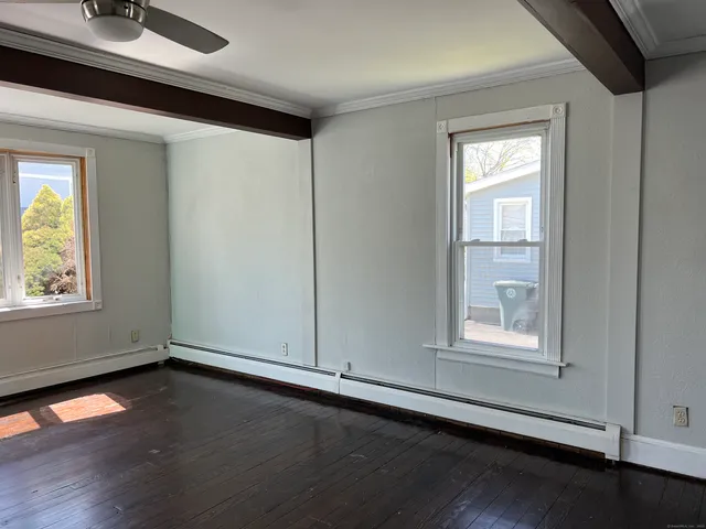 an empty room with wooden floor and windows