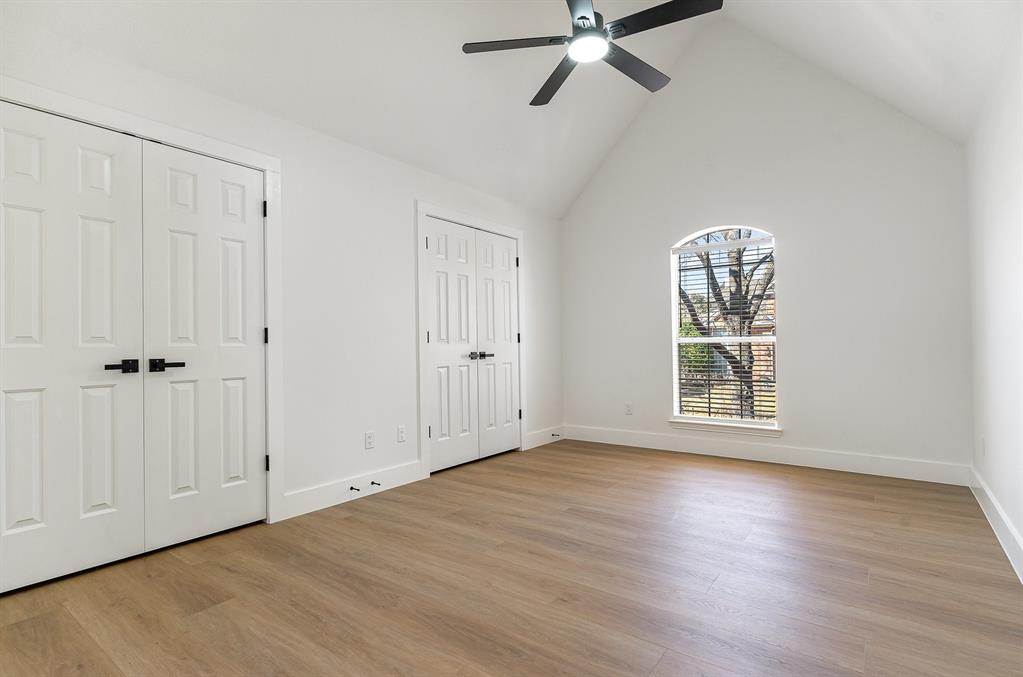 7524 Aberdon Road Dallas, TX 75252 - Photo 25 of 39 Unfurnished bedroom featuring multiple closets, light wood-style floors, a ceiling fan, high vaulted ceiling, and baseboards