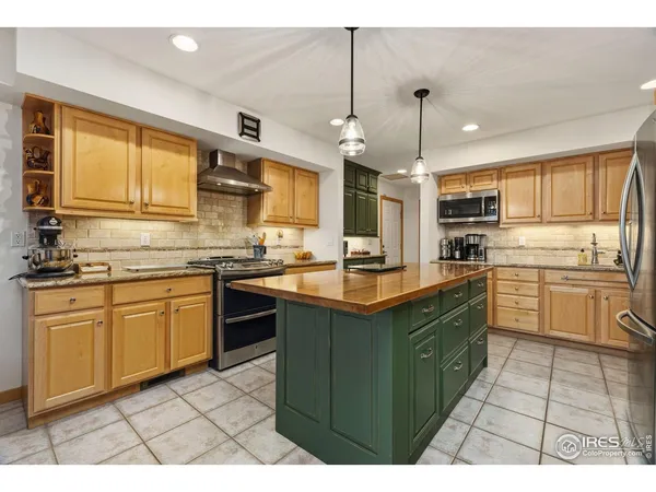 a dining hall with stainless steel appliances kitchen island granite countertop a table chairs and a living room view